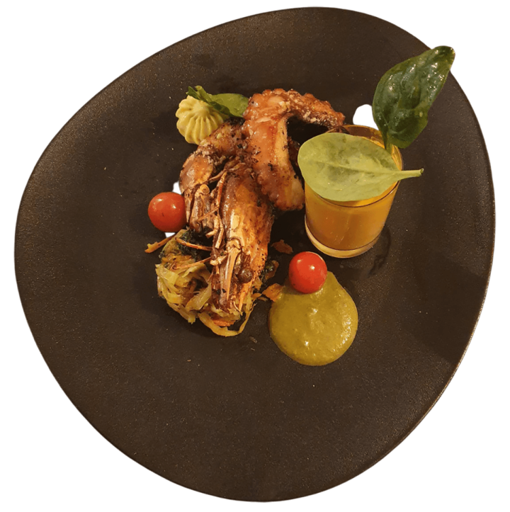 Plat de gambas grillées, accompagné de tomates cerises, d'une purée et d'une sauce garnie de feuilles d'épinards frais Martinique